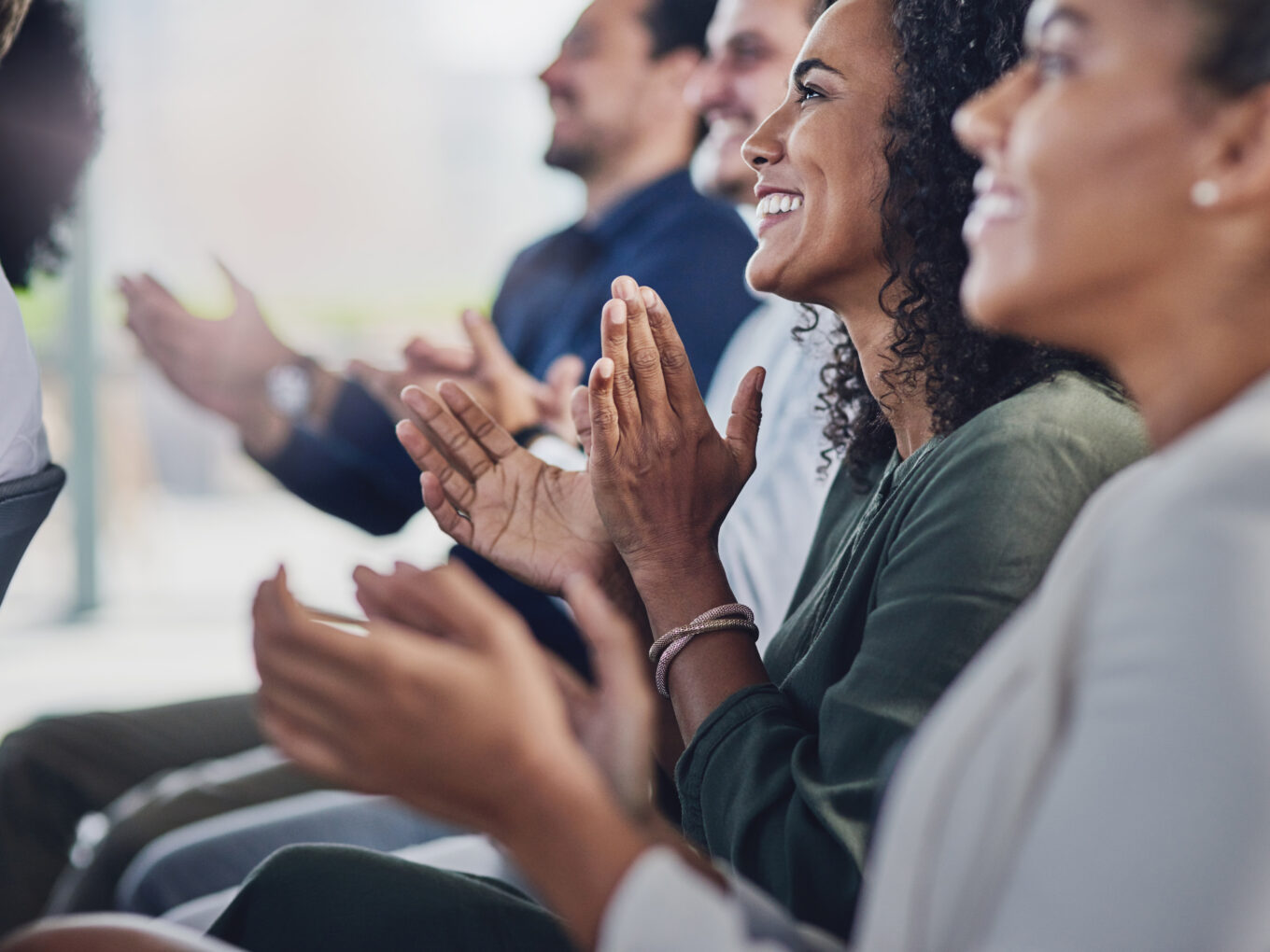 People in a row applauding during an event, smiling and engaged.