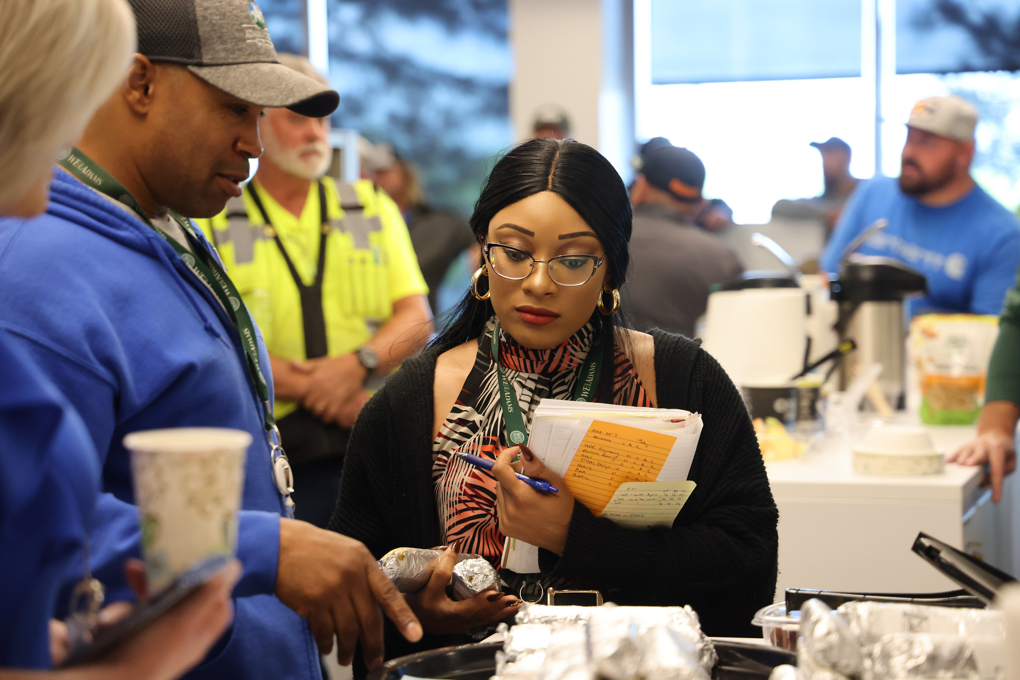 54382027606_b78c86a82e_k.jpg holding notes and pen, focused in a busy room.