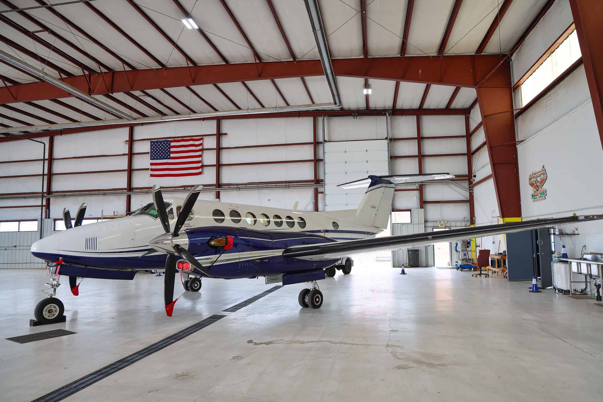 Aircraft inside hangar with American flag above.