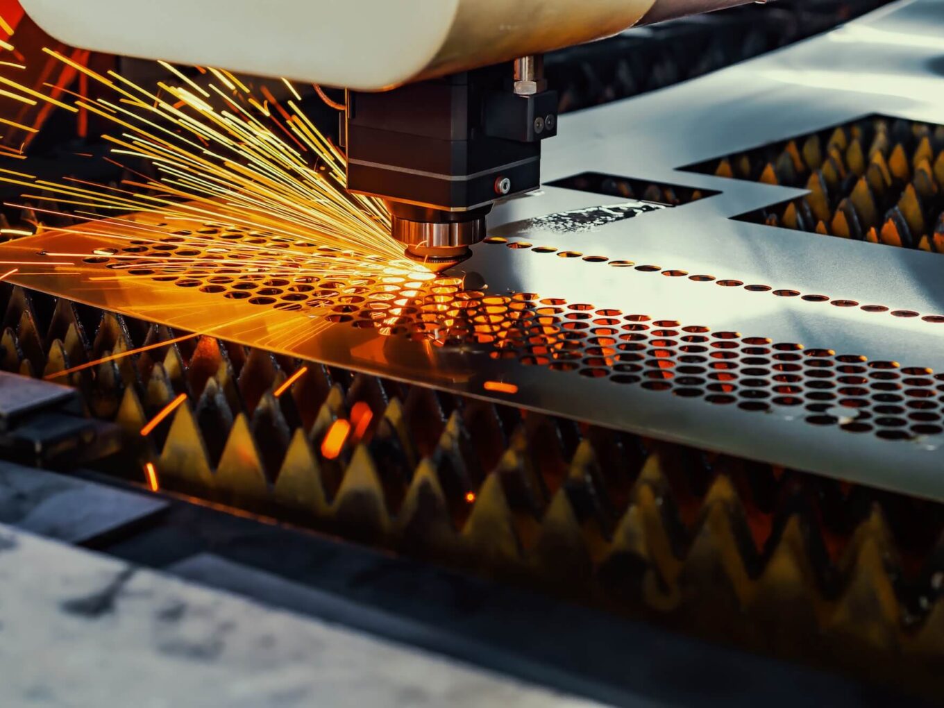 Laser cutting machine emitting sparks while processing metal sheet.