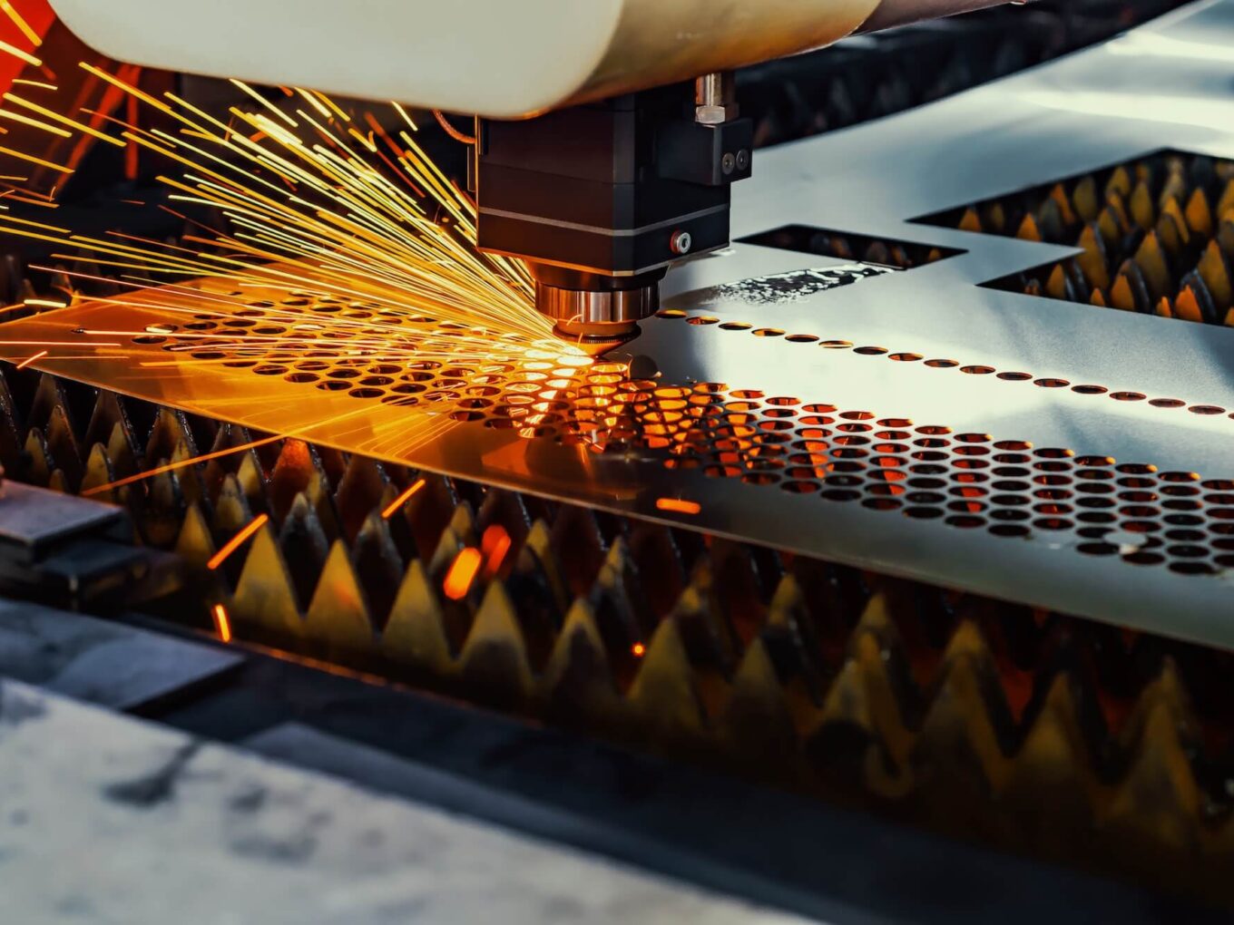 Laser cutting machine emitting sparks while processing metal sheet.