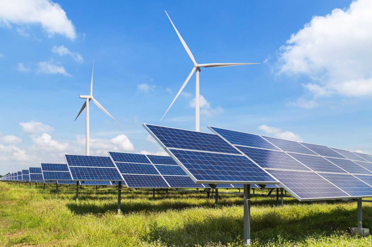 Solar panels and wind turbines under a blue sky.