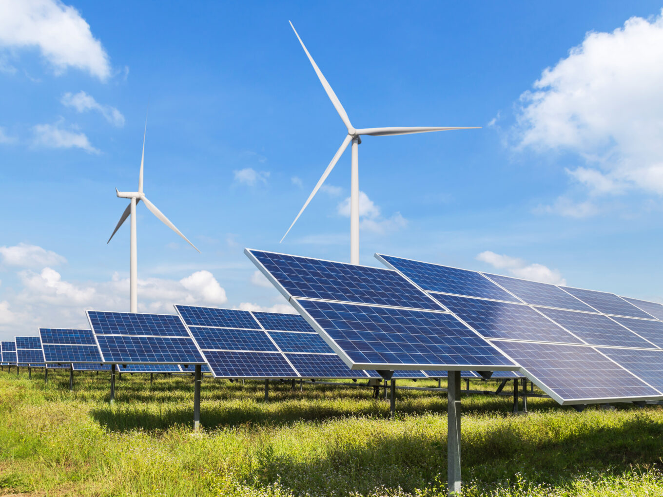 Solar panels and wind turbines under a blue sky.