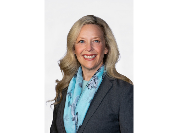 Jenni Hall smiling, wearing a blue scarf and gray blazer